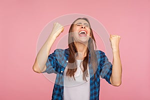 I am champion! Portrait of ecstatic successful girl in checkered shirt screaming for joy with raised fists