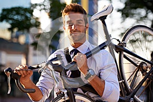 I choose the green way. an attractive young man carrying his bicycle on the way to work.