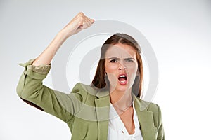 I demand more. Studio portrait of a young woman shaking her fist in anger against a grey background.