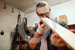 I did my best. a focused young male carpenter looking down the surface of a piece of wood that he sanded down inside of