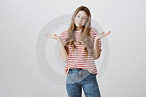 I do not care about rules. Portrait of indifferent careless teenage girl with blonde hair shrugging and holding spread