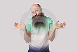 I don`t know. Portrait of puzzled or confused middle aged bald man with long beard standing with raised arms and looking at camer