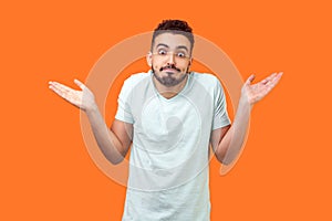 I don`t know, who cares. Portrait of confused clueless brunette man making no idea gesture. isolated on orange background