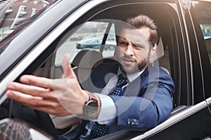 I don`t like it. Angry and emotional businessman in formal wear is gesturing and making a grimace while driving his car.