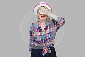 I don`t want to see it. Portrait of scared or shocked modern stylish mature woman in casual style in white hat standing and close