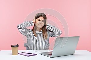 I dont hear you. Upset woman office worker covering ears and looking irritably at laptop screen, annoyed by unpleasant sound