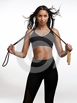 I dont skip my workouts. Studio portrait of a sporty young woman posing with a skipping rope around her neck against a