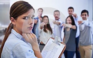 I dont think its going well. an anxious young woman facing the accusatory fingers of her coworkers.