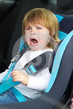 I dont wanna sit here Let me out. Portrait of a young baby crying while strapped into a car seat.