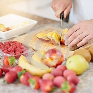 I eat good to feel good. a young man making a fruit salad in his kitchen.