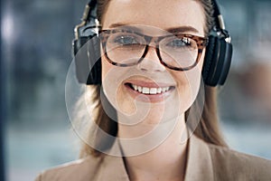 I enjoy listening to music while I stay productive. Portrait of a young businesswoman wearing headphones in an office.