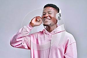 I enjoy the music!Young handsome african american man holds stylish silver earphones and smiles while looking at free space on a