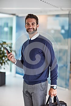 I always ensure that success is by my side. Portrait of a young businessman holding a cellphone and a bag.