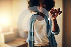 I finally have the keys to myself. Portrait of a cheerful young woman standing alone while holding up a pair of keys to