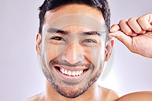 I find it slightly satisfying. Studio shot of a handsome young man tweezing his eyebrows.