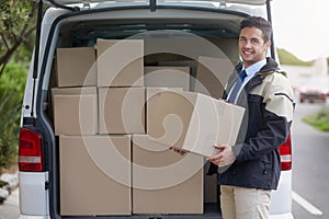 I get it right and on time, every time. Portrait of a friendly delivery man unloading cardboard boxes from his van.