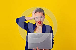 I got hacked.  Shocked business woman with laptop computer looking at screen isolated yellow background wall blue suit Human face
