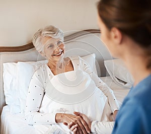 I had an amazing nights rest, thank you. a young nurse chatting with a senior woman in bed at a retirement home.