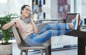 I had a moment and thought Id give you a call. a young designer talking on a cellphone while sitting with her feet up on