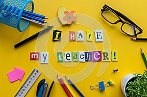 I hate my Teacher - text made with carved letters on yellow desk with office or school supplies on pupil table