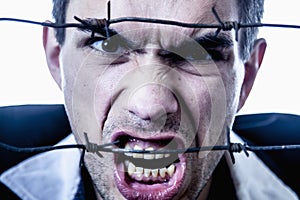 I hate social norms! Man screaming behind a barbed wire as symbol of  readiness to fight.