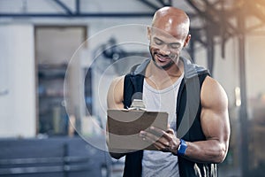 I have a day full of clients to train. a muscular young man writing notes on a clipboard while working in a gym.