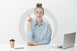 I have great idea. Smart attractive female office manager in stylish glasses, sitting near laptop and smartphone