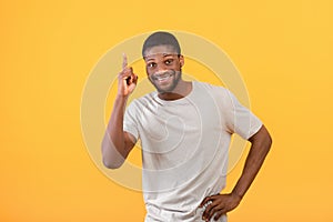I have idea. Inspired african american man raising finger up, standing over yellow studio background