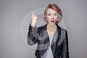 I have idea. Portrait of surprised beautiful girl with short hairstyle and makeup in casual style black leather jacket standing