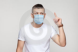 I have idea. Portrait of thoughtful young man in white shirt with surgical medical mask standing and try to remember his idea
