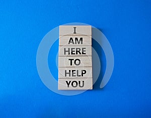 I am here to help symbol. Concept words I am here to help on wooden blocks. Beautiful blue background. Businessman hand. Business