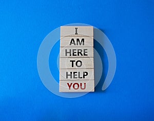 I am here to help symbol. Concept words I am here to help on wooden blocks. Beautiful blue background. Businessman hand. Business