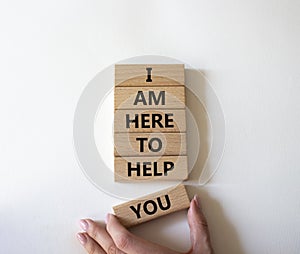 I am here to help symbol. Concept words I am here to help on wooden blocks. Beautiful white background. Businessman hand.