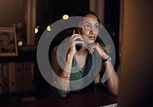 I hope my colleague is still awake to help me. a young businesswoman talking on a cellphone while using a computer in an