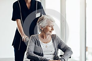 I hope you get the care you need in your grey years. a senior woman in a wheelchair being pushed by a female nurse.