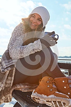 I just cant help but to love winter. a beautiful woman enjoying a hot beverage while sitting outside in the snow.