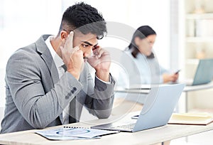 I just need to focus...a young businessman looking stressed out while working on a laptop in an office.