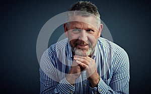 I keep my business dealings casual. Studio shot of a confident and mature businessman looking thoughtful against a dark