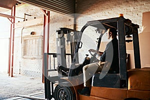 I keep things moving on the warehouse floor. a young male warehouse worker driving a forklift.