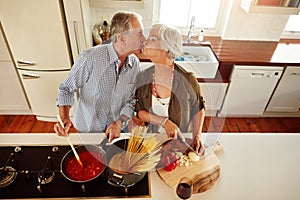 I kiss better than I cook. an affectionate couple preparing a meal in the kitchen.