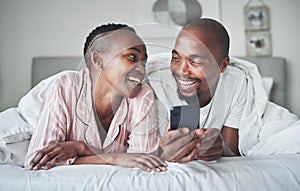 I knew youd appreciate this. a happy young couple using a smartphone together in the bedroom at home.
