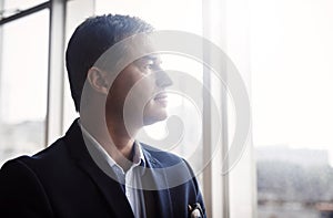 I know what I want and how Ill achieve it. a mature businessman looking out a window in an office.