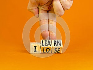 I learn or lose symbol. Concept words I learn and I lose on wooden cubes. Businessman hand. Beautiful orange table orange