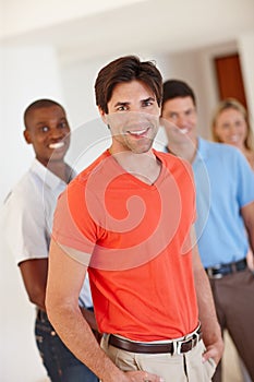 I like the casual work environment. Portrait of a handsome businessman in casualwear with his colleagues standing behind