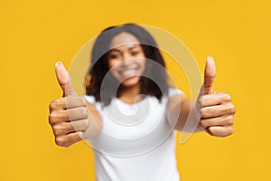 I like It. Happy african american lady gesturing thumbs up with both hands over yellow background, selective focus