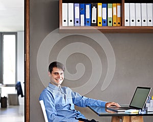 I like having everything neat and tidy in here. Portrait of a confident young businessman sitting at his office desk.