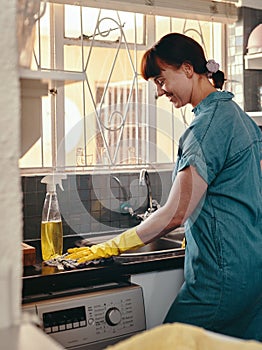 I like my kitchen spick and span. an attractive young woman using cleaning detergent to clean her kitchen at home.