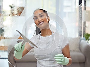 I like my windows clear like crystal. Shot of an attractive young woman standing alone at home and cleaning her windows.
