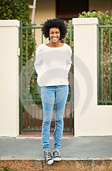 I live in a great neighborhood. Portrait of a happy young woman standing on the sidewalk outside of her home.