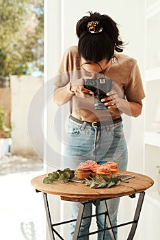 I love blogging. an attractive young businesswoman standing and using her camera to photograph cupcakes for her blog.